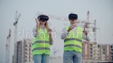 两个人一男一女戴着虚拟现实眼镜在建筑背景下使用起重机